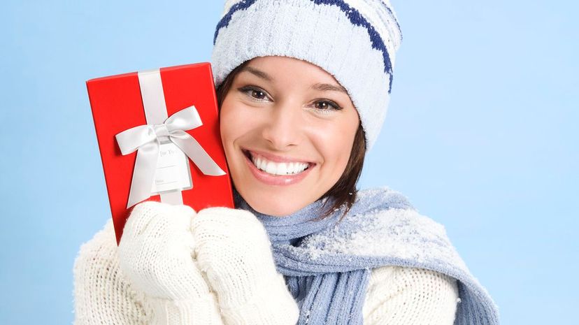 Beautiful woman in winter sweater holding gift