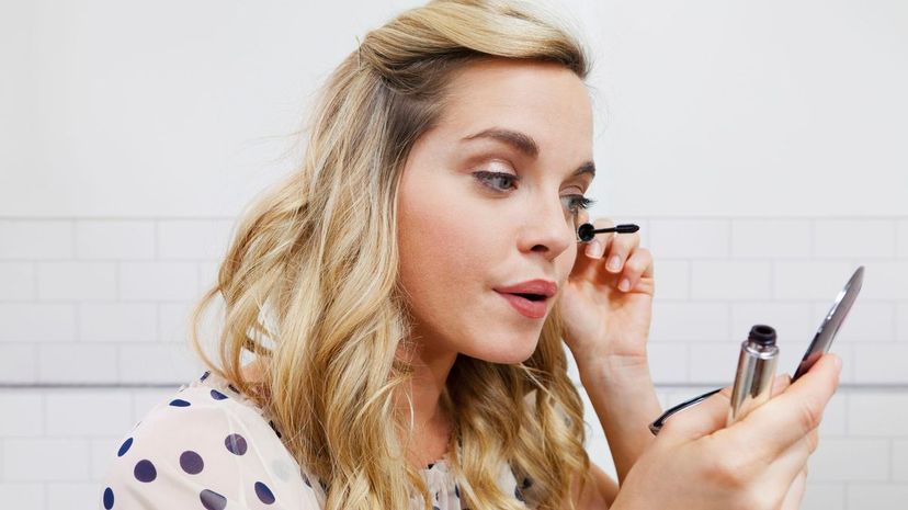 Woman applying mascara in mirror