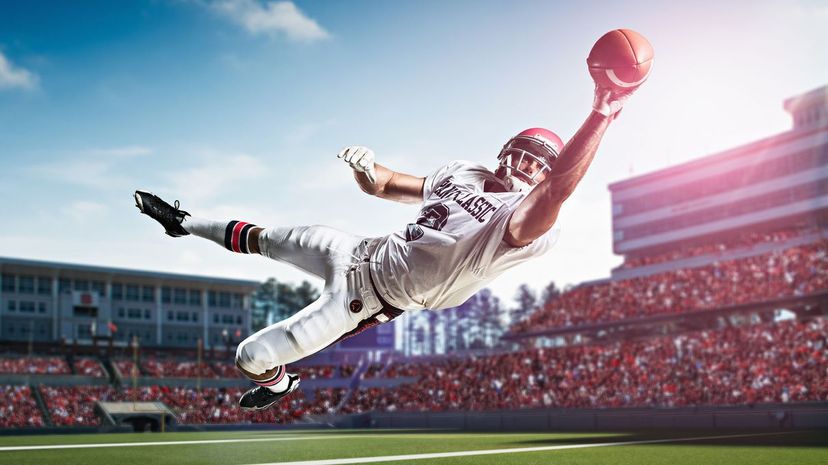 American football player catching ball mid air in stadium