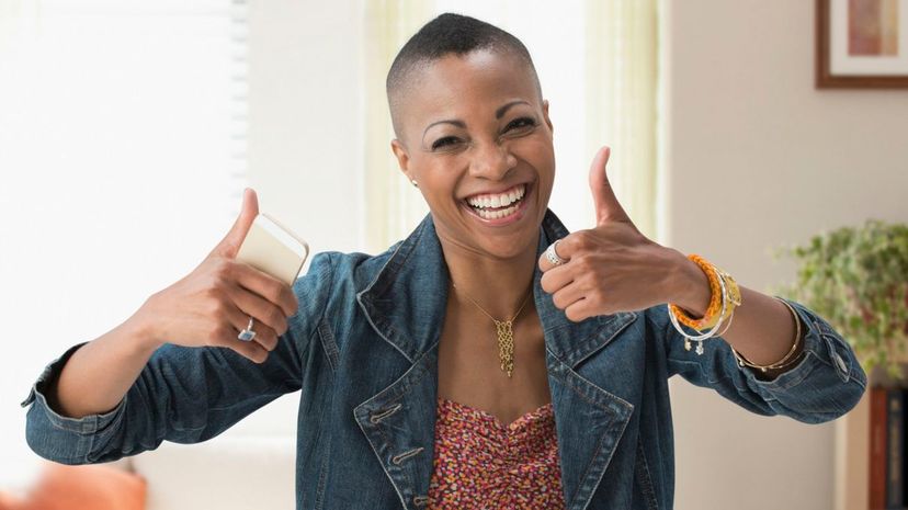 Black woman giving thumbs up in living room