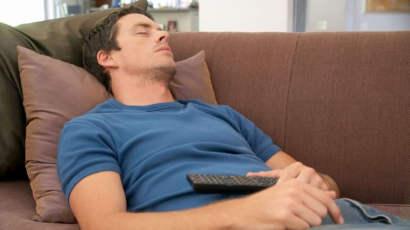 Man sleeps on sofa with TV remote