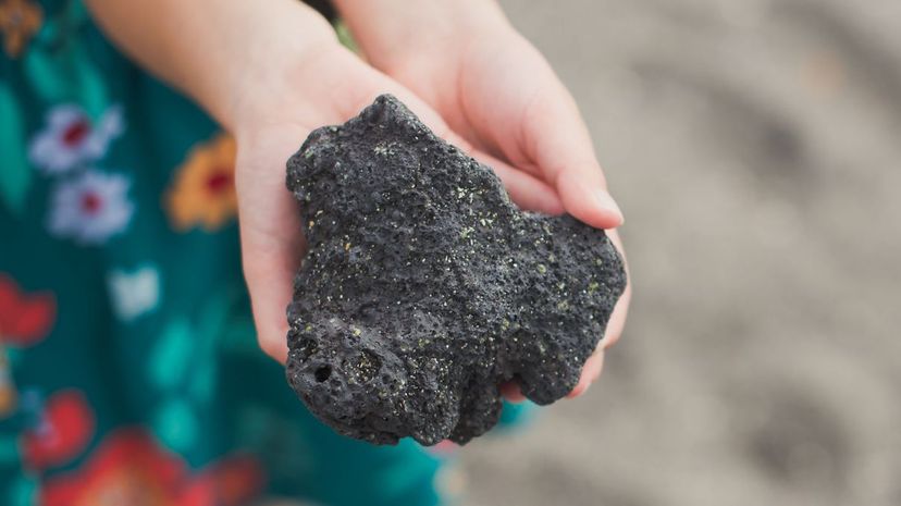 Girl's hands holding lava rock in Hawaii