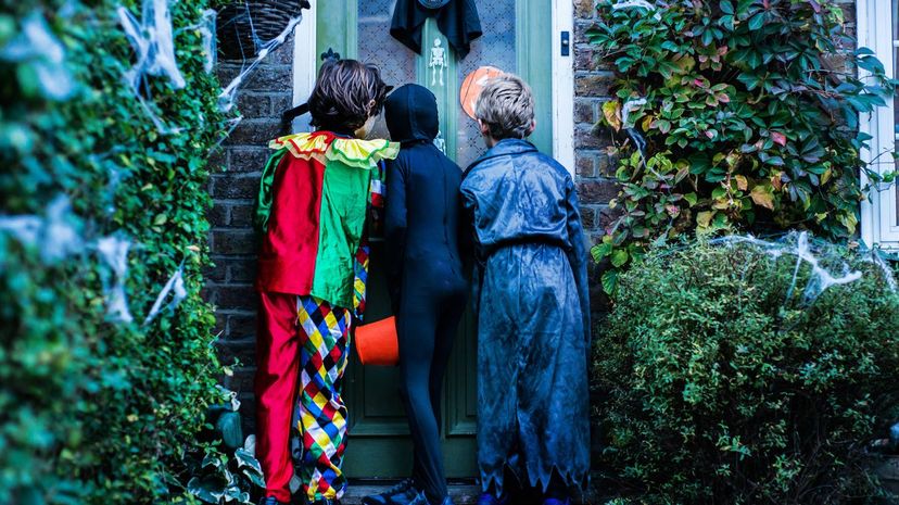 Three boy in halloween costumes, standing at door, trick or treating