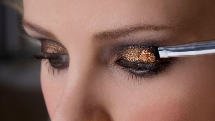 Young woman applying glitter eye shadow
