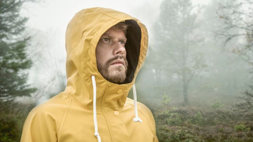 Man in misty forest wearing hooded yellow raincoat