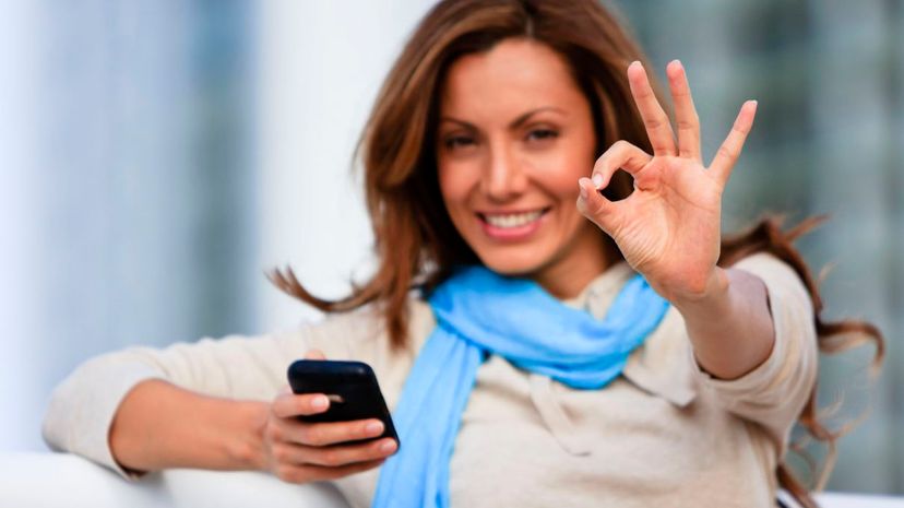 Woman holding cellphone and giving okay sign
