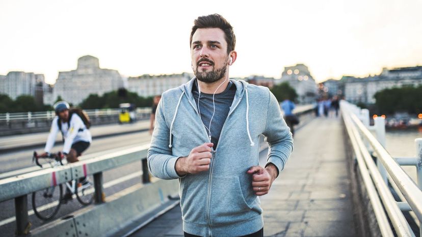 Man with earphones running on the bridge