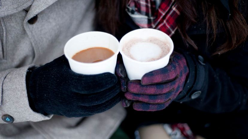 Young couple in winter gloves holding takeaway drinks