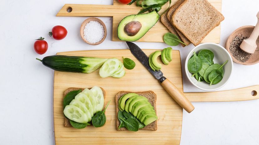 Avocado, spinach and cucumber toasts on cutting board