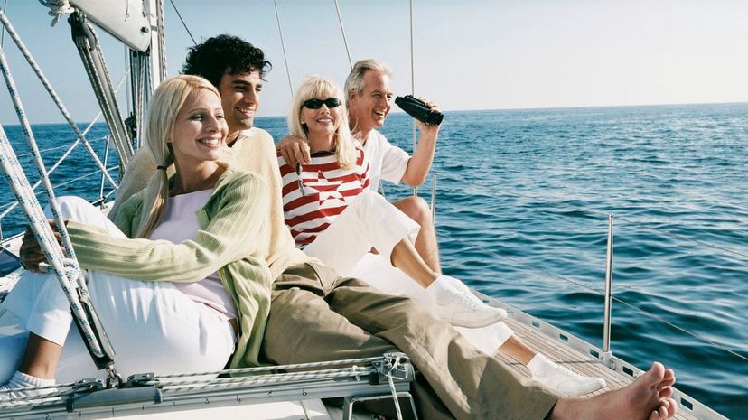 Mature Couple and Young Couple Sit on the Deck of a Yacht Looking at the View