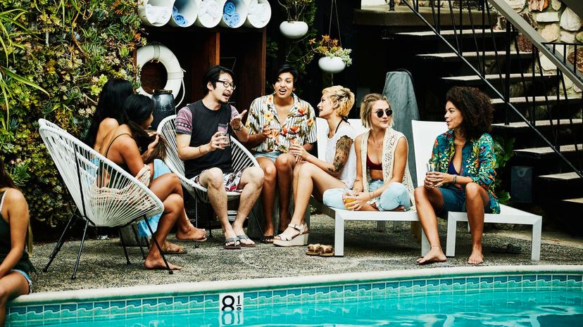 Group of friends in discussion during party by pool hotel