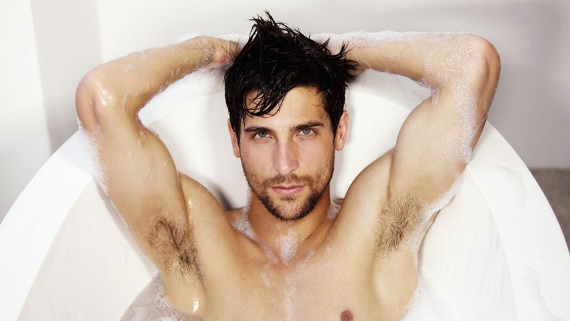 handsome man in bathtub shirtless hands behind head
