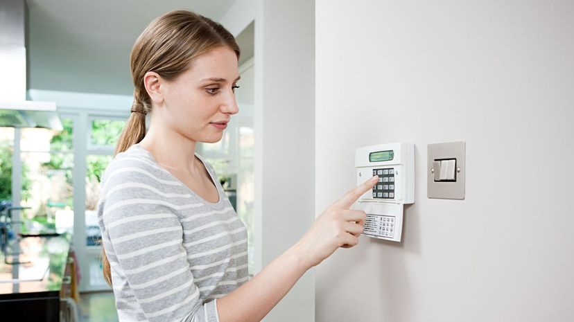 Woman setting burglar alarm