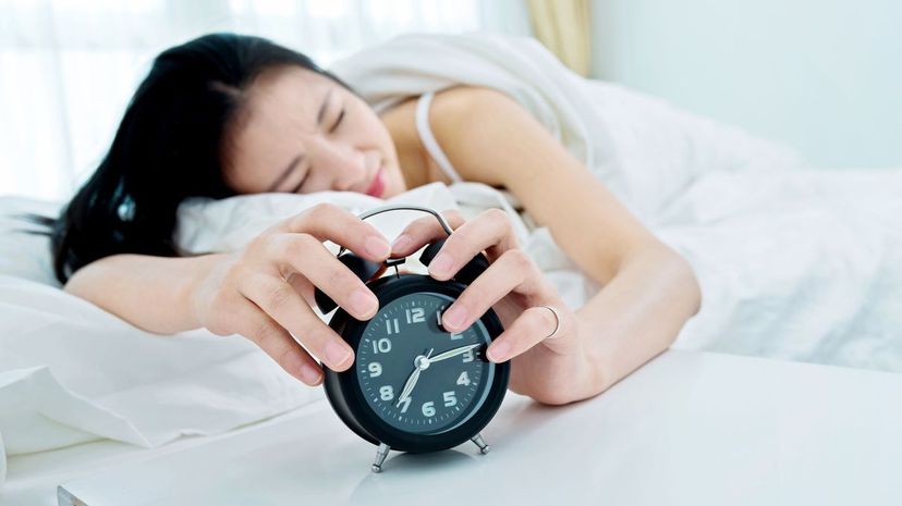 Woman turning off alarm clock