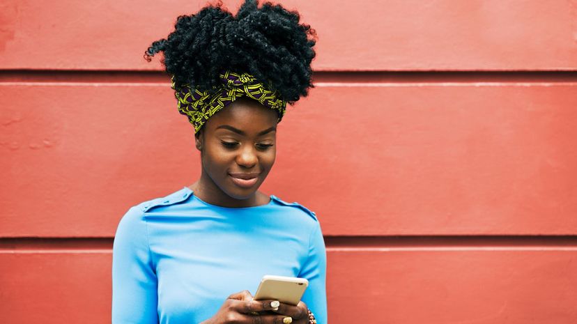 Woman Texting in Front of Wall