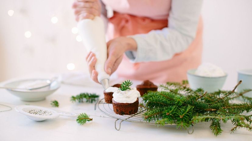Woman icing chocolate cupcakes with whipped cream