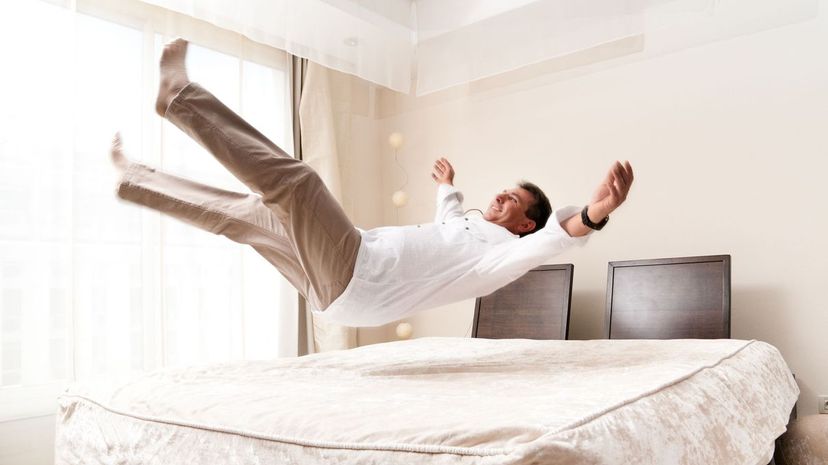 Mid adult man jumping to bed