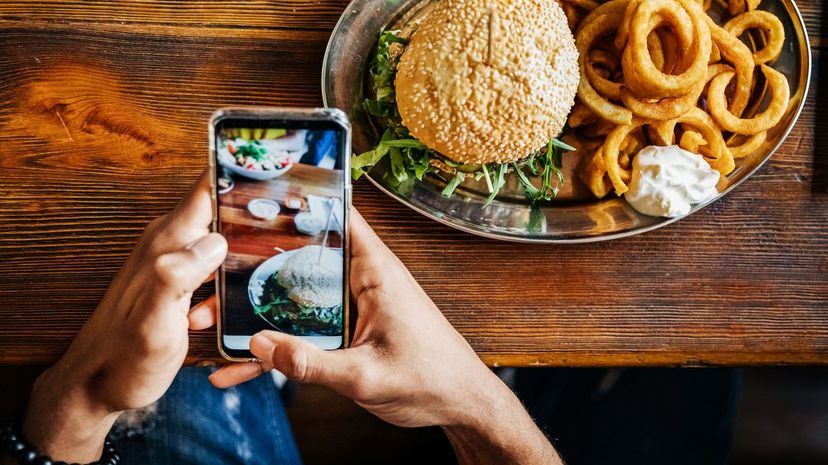 Man Taking Picture Of Burger With Smartphone