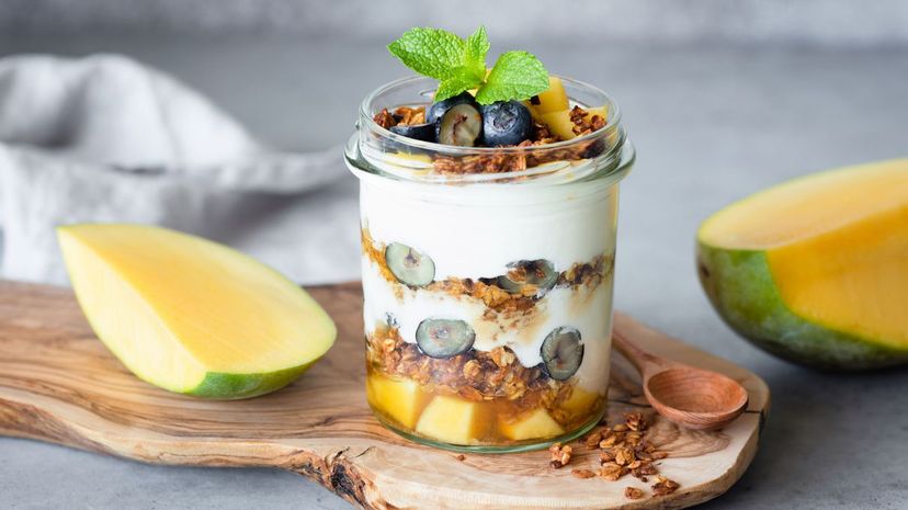 Breakfast yogurt parfait with granola, mango, berries in jar
