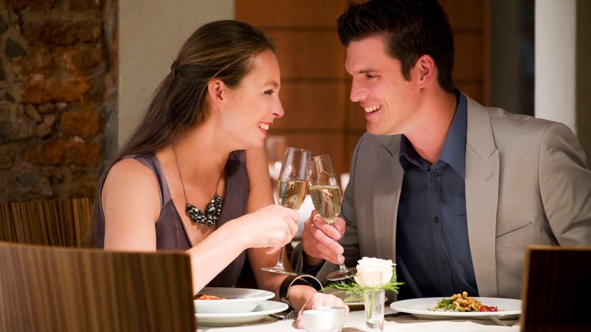 Couple toasting champagne glasses at restaurant table