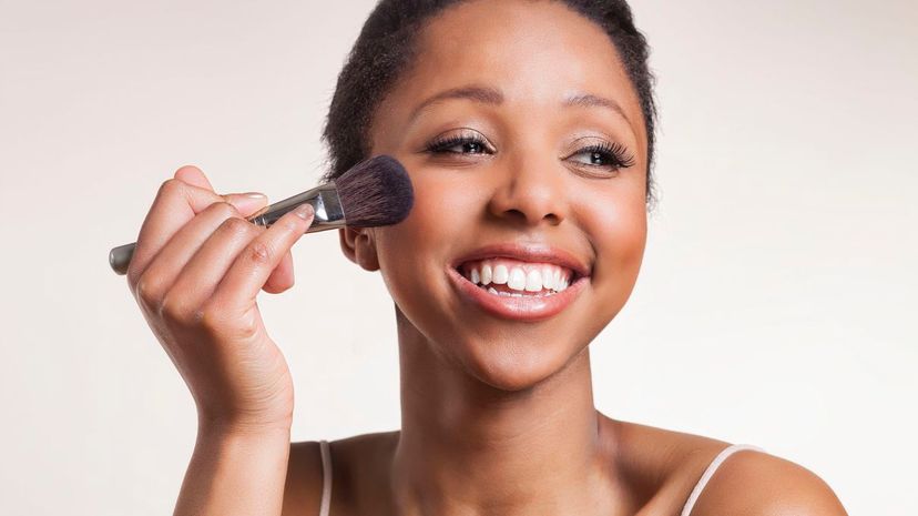 Lady laughing while applying blush brush on cheeks