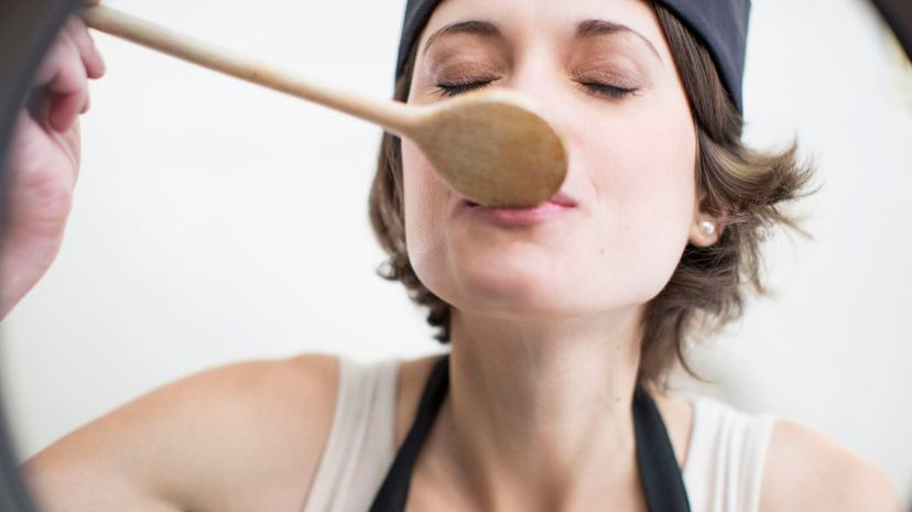 Woman tasting food from saucepan