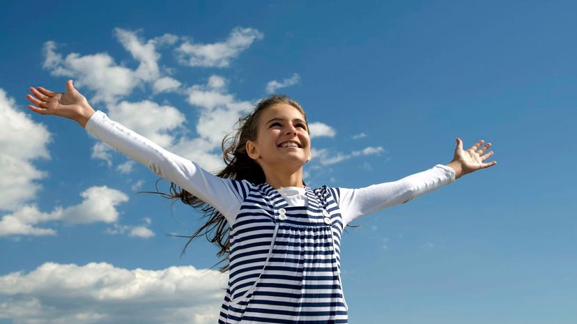 Happy young girl opens her hands up on a sky