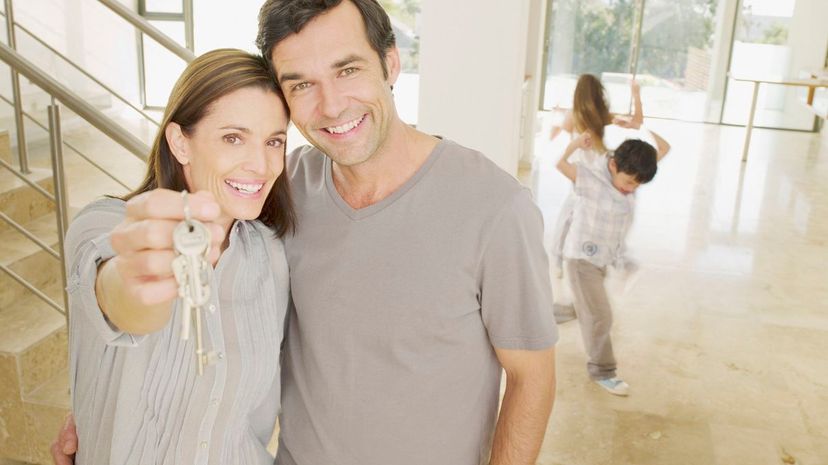 Happy couple holding keys in new house