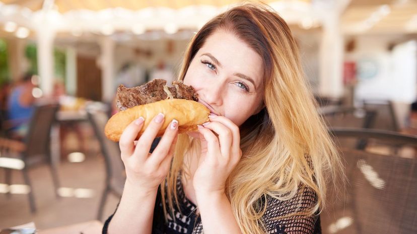 Young woman eating steak sandwich