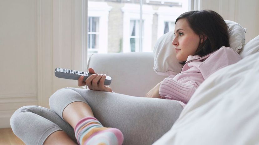 Young woman relaxing on sofa using remote control