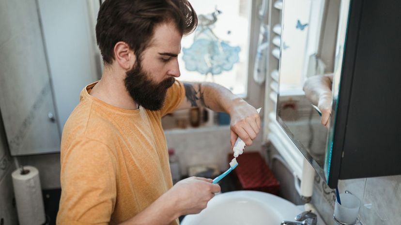 Man in pajamas applying toothpaste on the toothbrush