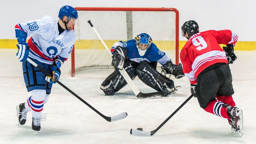 Ice hockey goalkeeper trying to catch puck in ice hockey stadium