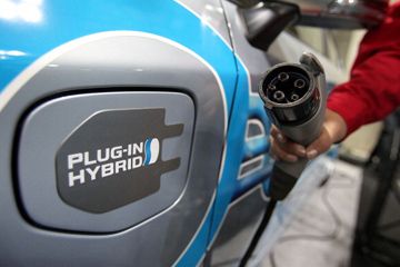 A member of the Toyota staff holds a charging plug next to a Toyota Prius Plug-in Hybrid during EV JAPAN, in Tokyo.