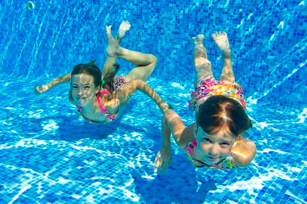 Child having fun swimming in summer pool.