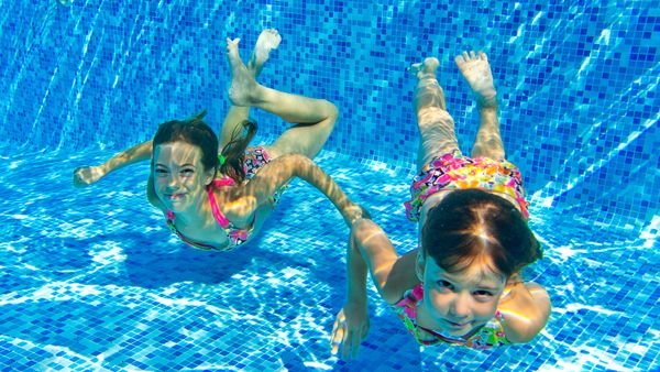 Child having fun swimming in summer pool.