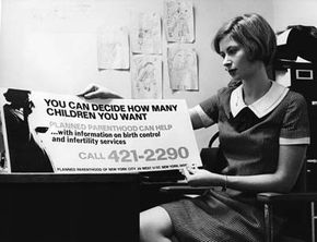 In December 1967, birth control information, which was to be displayed on New York buses, is held up for scrutiny by Marcia Goldstein, the publicity director of Planned Parenthood.