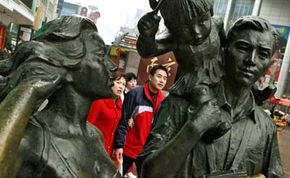 A Chinese couple walks toward a statue of a model one child family on the Nanjing Rd shopping area of Shanghai. China will focus on correcting a potentially destabilizing gender imbalance over the coming years.