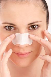 Young woman cleaning her skin with clear-up strip (beauty concept)