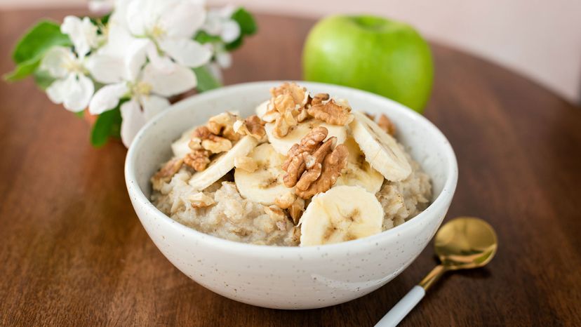 Oatmeal porridge with banana and walnuts in bowl.