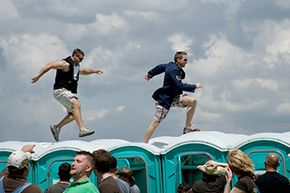 Two men dash across the tops of porta-potties in the infield at the Kentucky Derby at Churchill Downs, 2008. The porta-potty race is an unofficial Kentucky Derby tradition.
