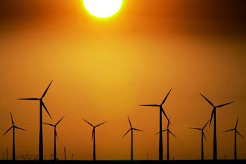 A group of wind turbines are silhouetted by the setting sun on a wind farm near Montezuma, Kan.
