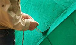 It's a good idea to stake your tent to the ground to prevent it from blowing away in rough weather. If you don't have any stakes, tie the tent down to nearby trees instead.