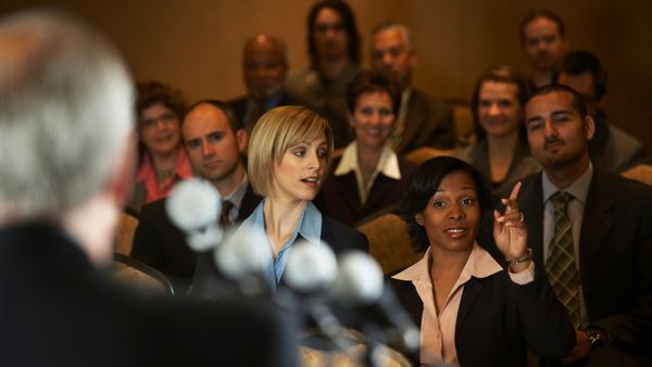 Man Speaking at a Press Conference Filled with Reporters