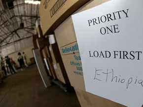 Project C.U.R.E. boxes with volunteers in the background