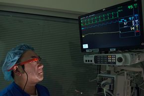 A doctor wearing Google Glass looks at a patient's vitals screen.