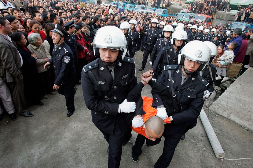 Chinese police escort a convicted murderer to a public sentencing on Nov. 17, 2004 in Chongqing, China. More than 10,000 watched. China Photos/Getty Images