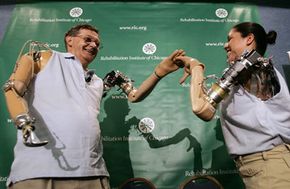 Jesse Sullivan (left) and Claudia Mitchell (right) high-five each other as they demonstrate the functionality of their thought-controlled bionic arms during a news conference in Washington, D.C.
