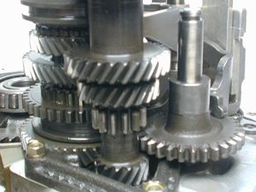 Most of the gears in a manual transmission have helical teeth. The three gears that make up reverse have straight teeth. The large spur gear on the right slides up to put the car in reverse.