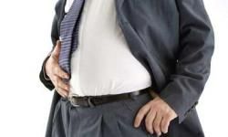 Mature businessman, one hand on hip, one hand on belly, mid section