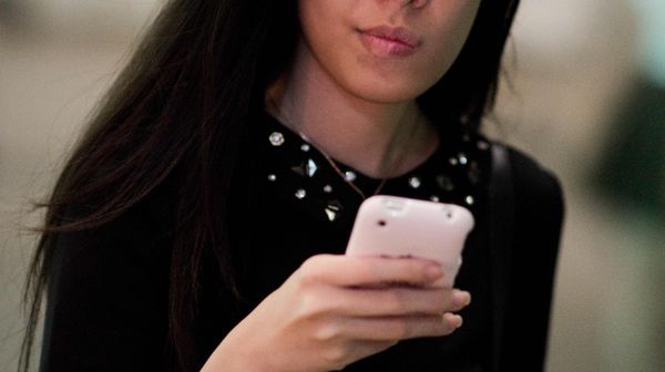 A woman looks at her smartphone.